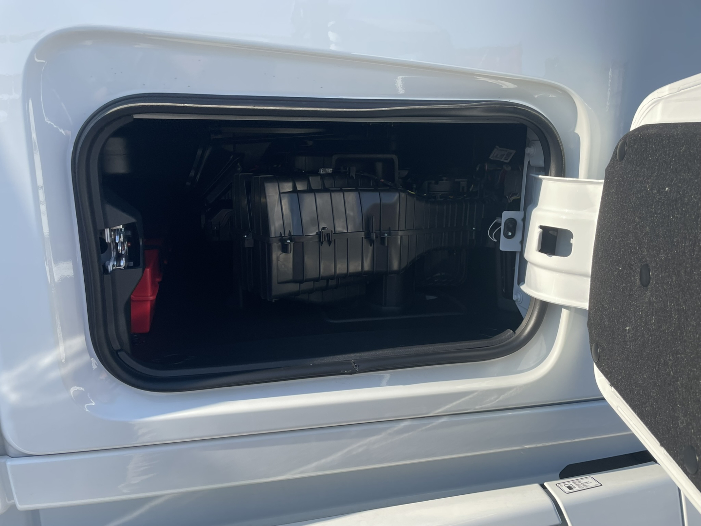 Rear view of Volvo VNL64T860 cab with raised hatch showing engine bay area and some labeled components inside the compartment.