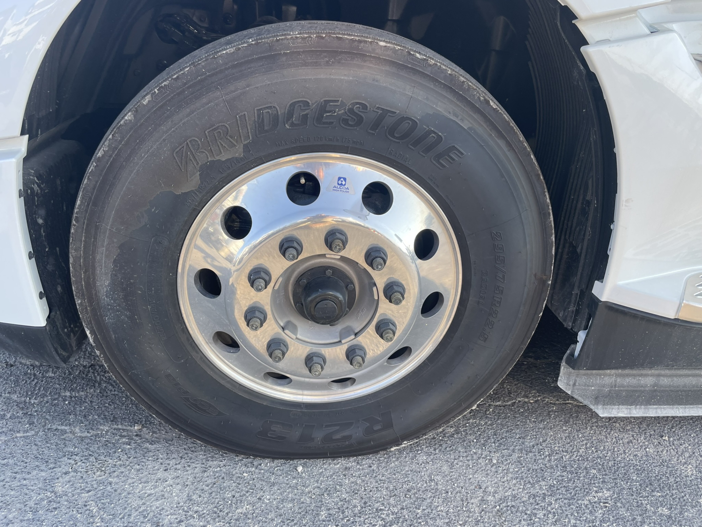 Bridgestone tire mounted on a Volvo VNL64T860 front wheel with polished aluminum hub and lug nuts visible; wheel well and fender in view.
