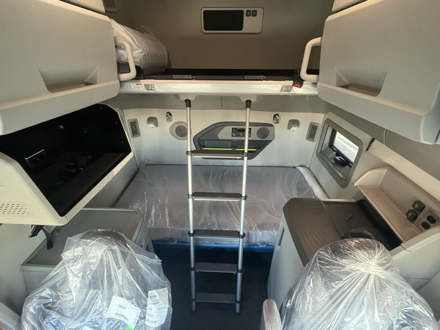Volvo VNL64T860 sleeper cab interior showing ladder in upper bunk area and storage compartments.