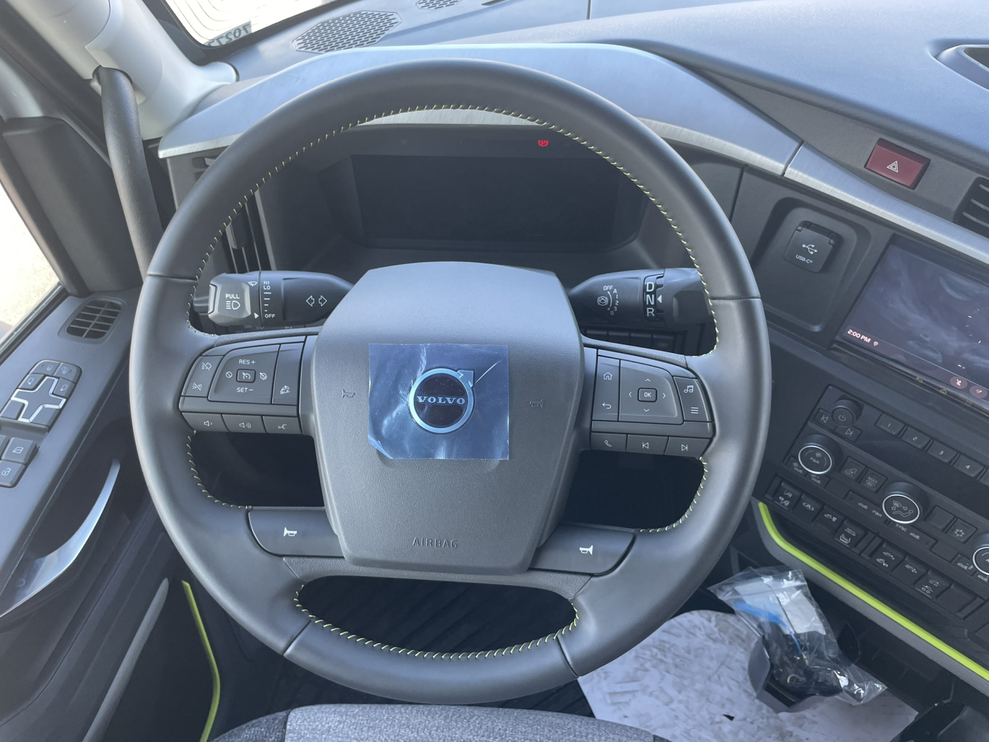 Volvo interior showing steering wheel and dashboard in the VNL64T860 truck showing Volvo emblem on center, control buttons on steering wheel, digital dash, and center console.