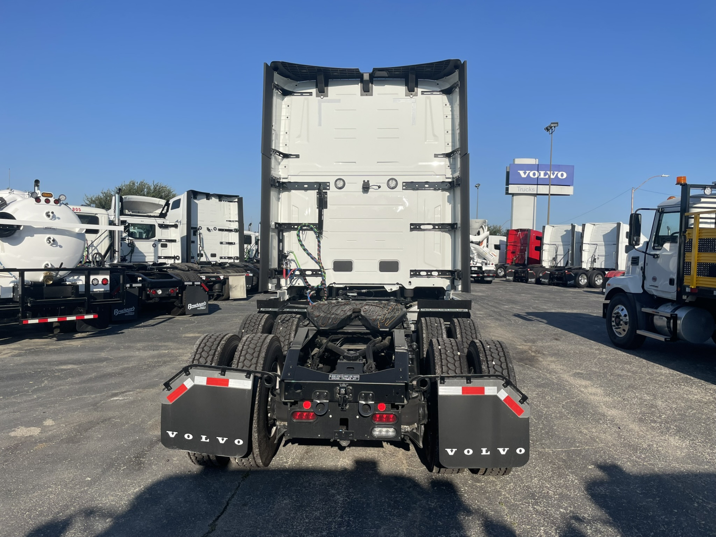 Rear view of a 2026 Volvo VNL64T860 truck tractor with fifth wheel and dual rear axles, Volvo mud flaps, and trailer hitch area visible.