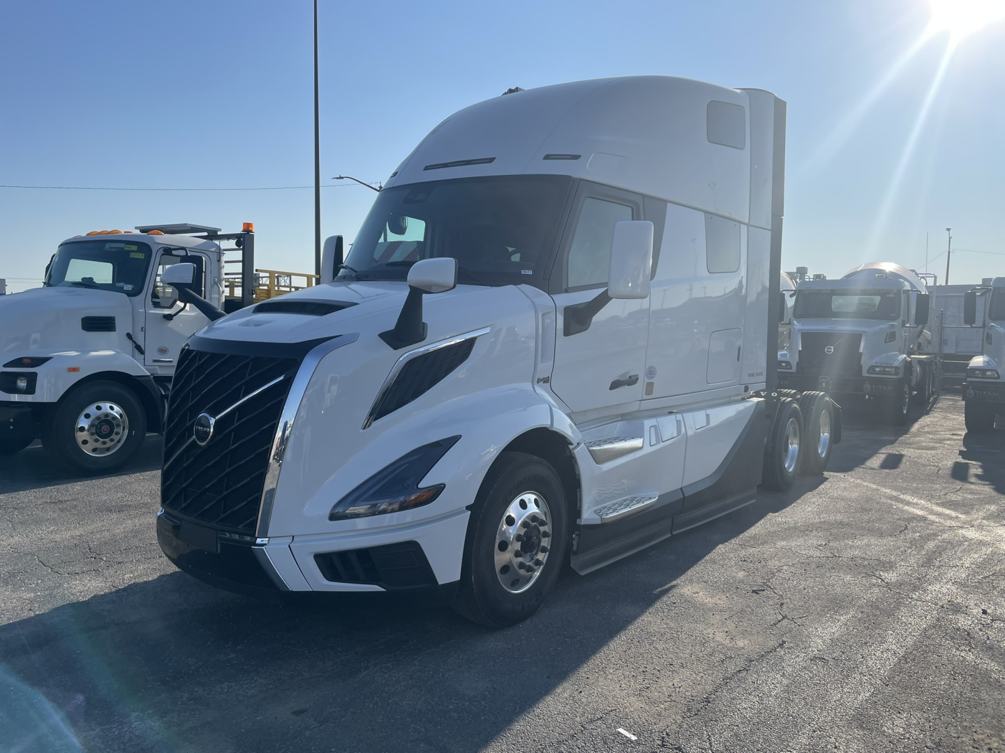 Volvo VNL64T860 sleeper cab truck in dealership lot, white with aerodynamic hood and large sleeper, front-left view.