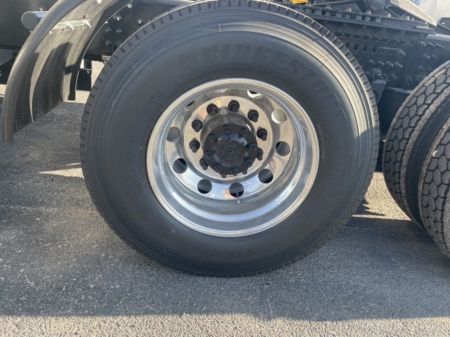 Wheel and tire close-up from a Volvo VNL64T860 truck showing the Bridgestone tire on a polished aluminum wheel with lug nuts.