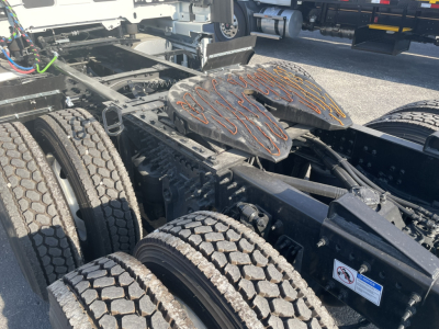 Truck chassis with dual rear axles and leaf spring suspension showing fifth wheel and tires; Volvo VNL frame components visible.