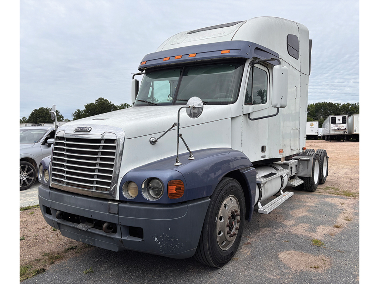 Truck image: 2003 Freightliner C120 Century Class conventional sleeper tractor, side view with chrome grille, dual rear axles, white cab.