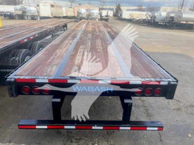 Flatbed trailer deck with WABASH branding and rear lights; shows steel flatbed with wooden planks and rear bumper/bar with red and white reflective tape.