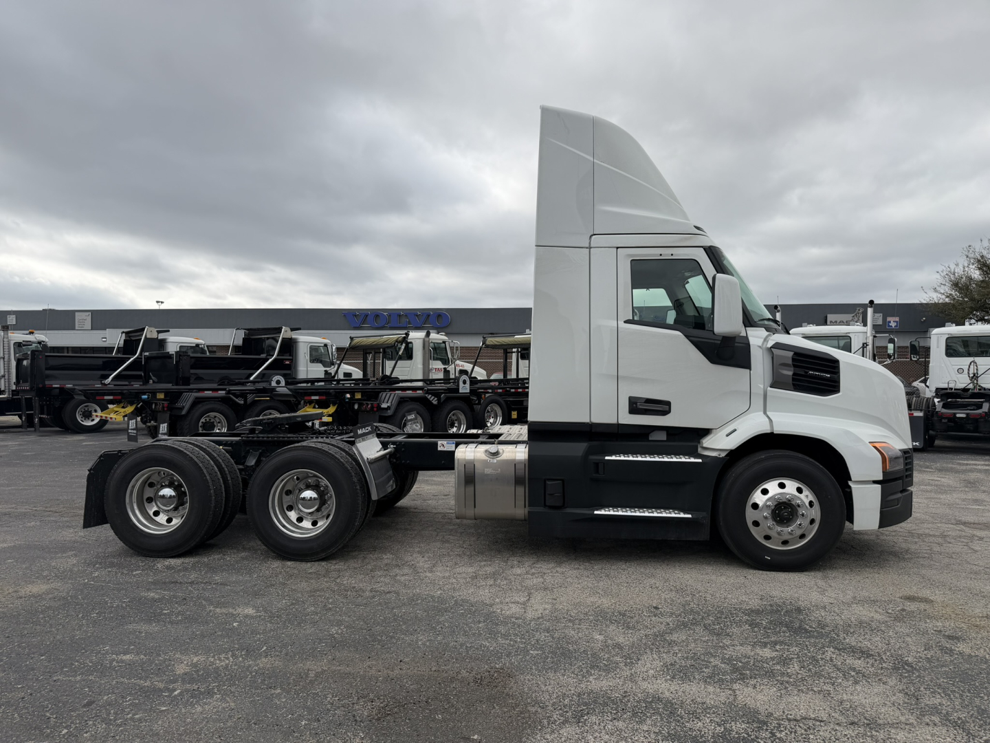 Side view of a white Mack AN64T conventional daycab tractor with dual rear axles, showing cab, fuel tank, and wheels.