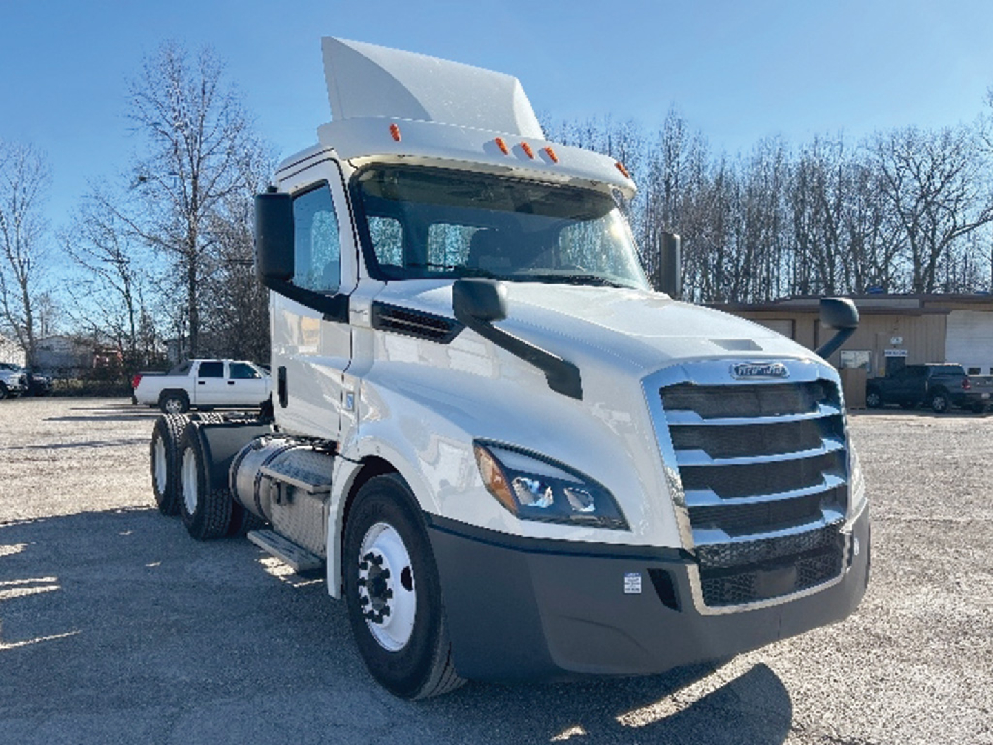 Truck image showing a 2019 Freightliner Cascadia 126 daycab in white with large grille, dual headlights, and elevated sleeper area, front right view.