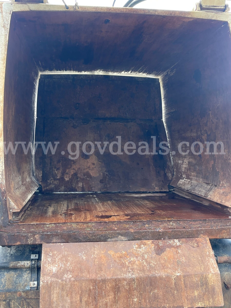 Dump truck bed interior showing rust and wear with open tailgate, cargo area empty.