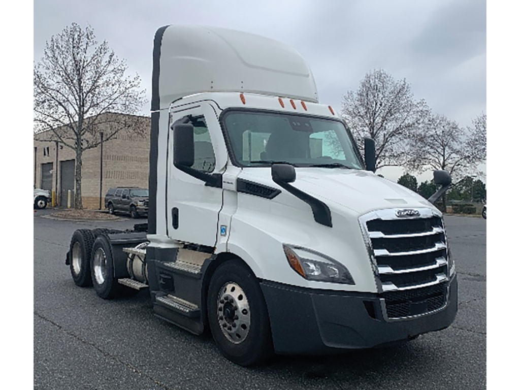 Truck cab from a Freightliner Cascadia showing front grille and side mirror in a parking lot.