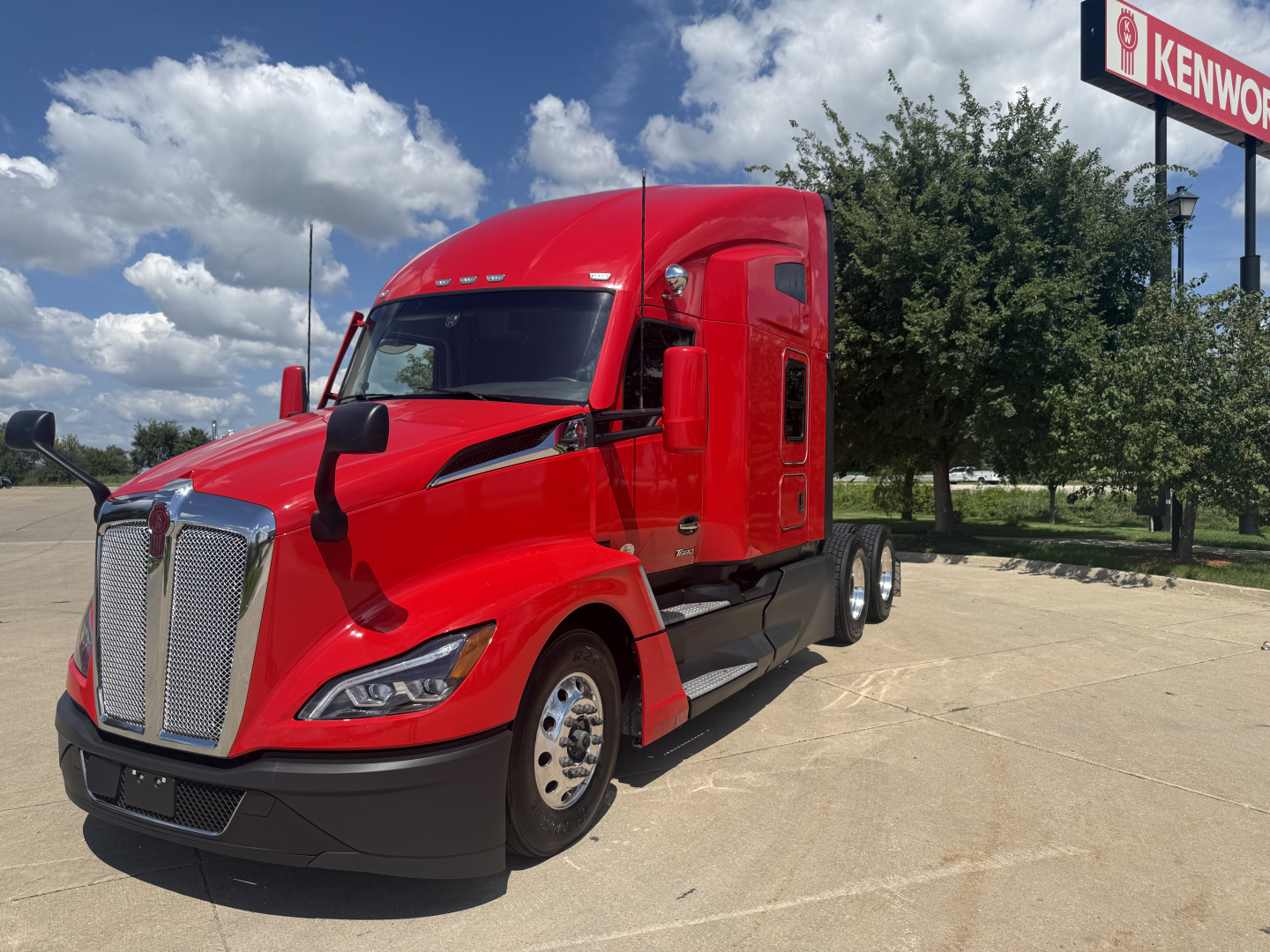 Kenworth T680 truck in red, front-left view. No text visible on body besides tug-of-war branding; large chrome grille, headlights, and Kenworth emblem.