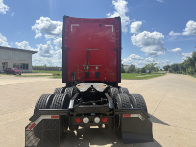 Kenworth T680 rear view showing fifth wheel, dual rear axles, and red sleeper cab. Visible are back of cab, trailer connection points, and rear bumper with lights.