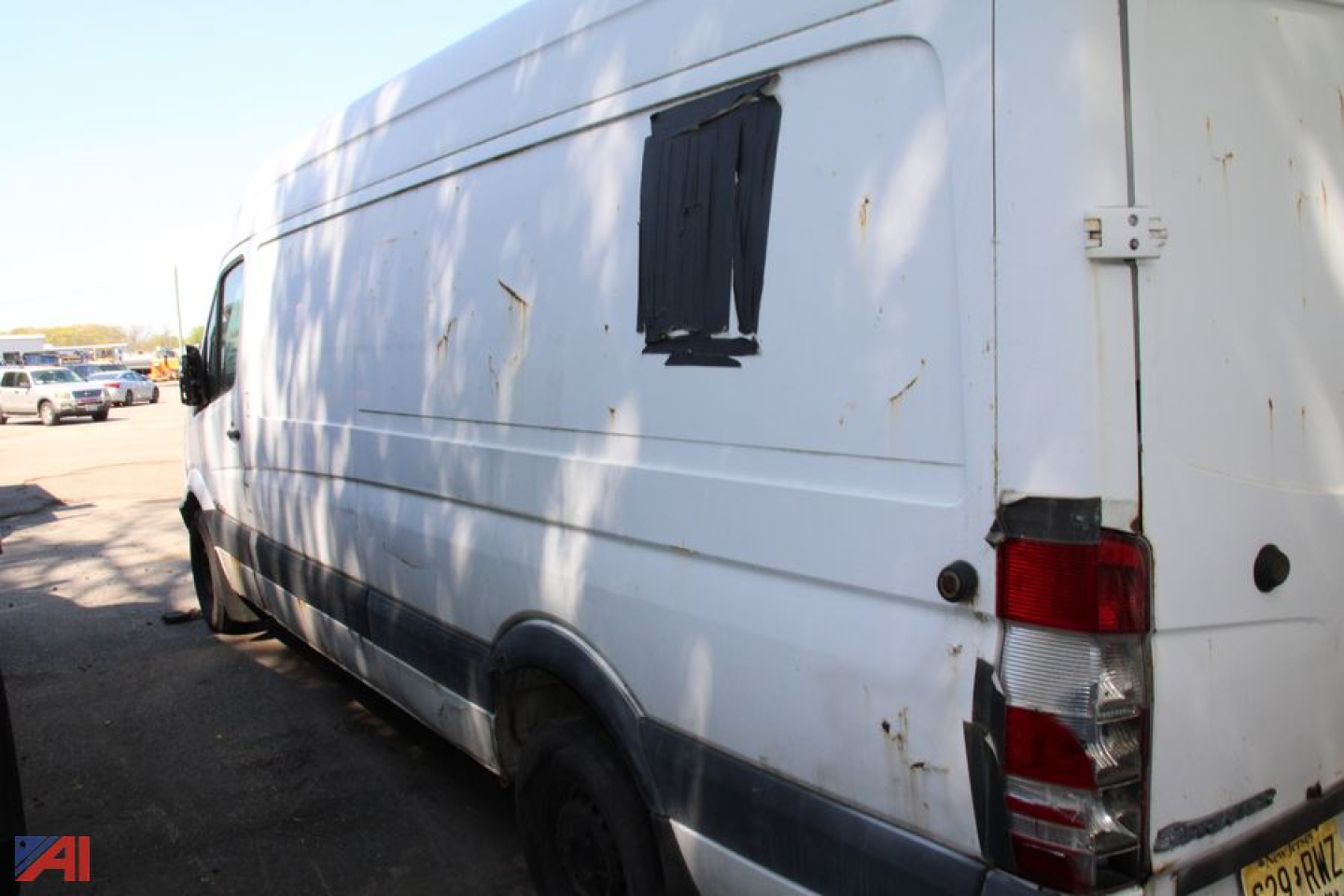 Cargo van side and rear view of a white 2007 Dodge Sprinter cargo van with a taped window patch on the side panel, rear door hinge, and taillight visible.