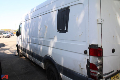 Cargo van side and rear view of a white 2007 Dodge Sprinter cargo van with a taped window patch on the side panel, rear door hinge, and taillight visible.