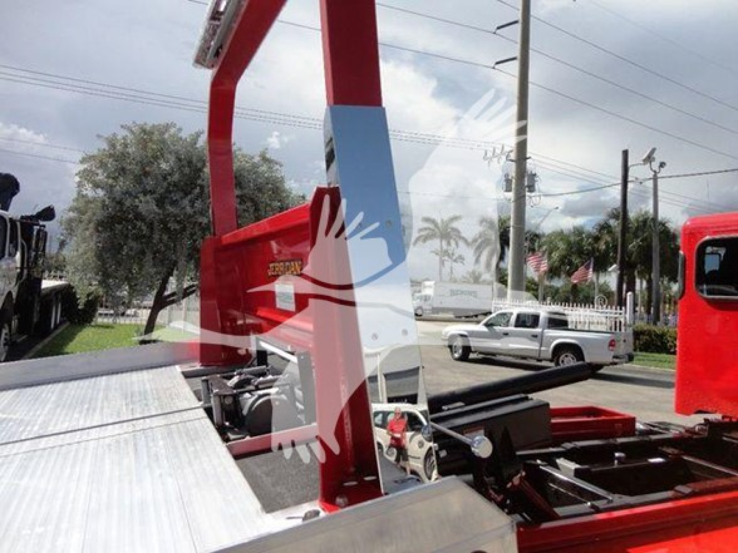 Vehicle equipment image showing a red rollback boom and platform on a Peterbilt 337 truck bed with metal decking and hydraulic components.