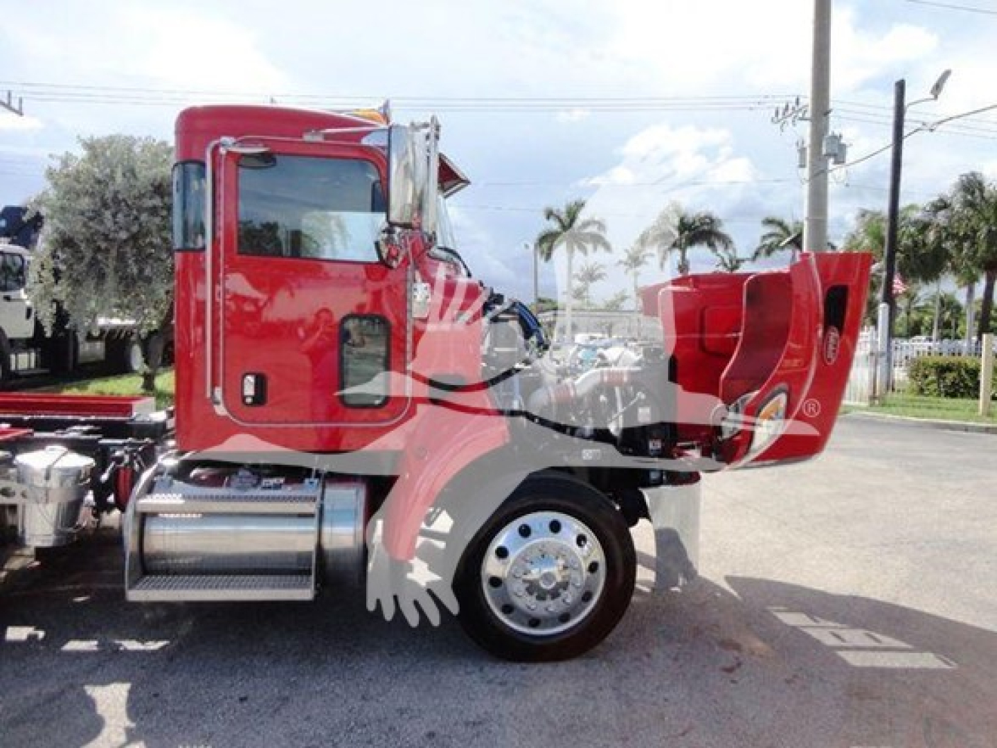 Red 2022 Peterbilt 337 rollback truck side view showing cab door, exhaust stack, chrome fuel tanks, and red bed with caution stripes.