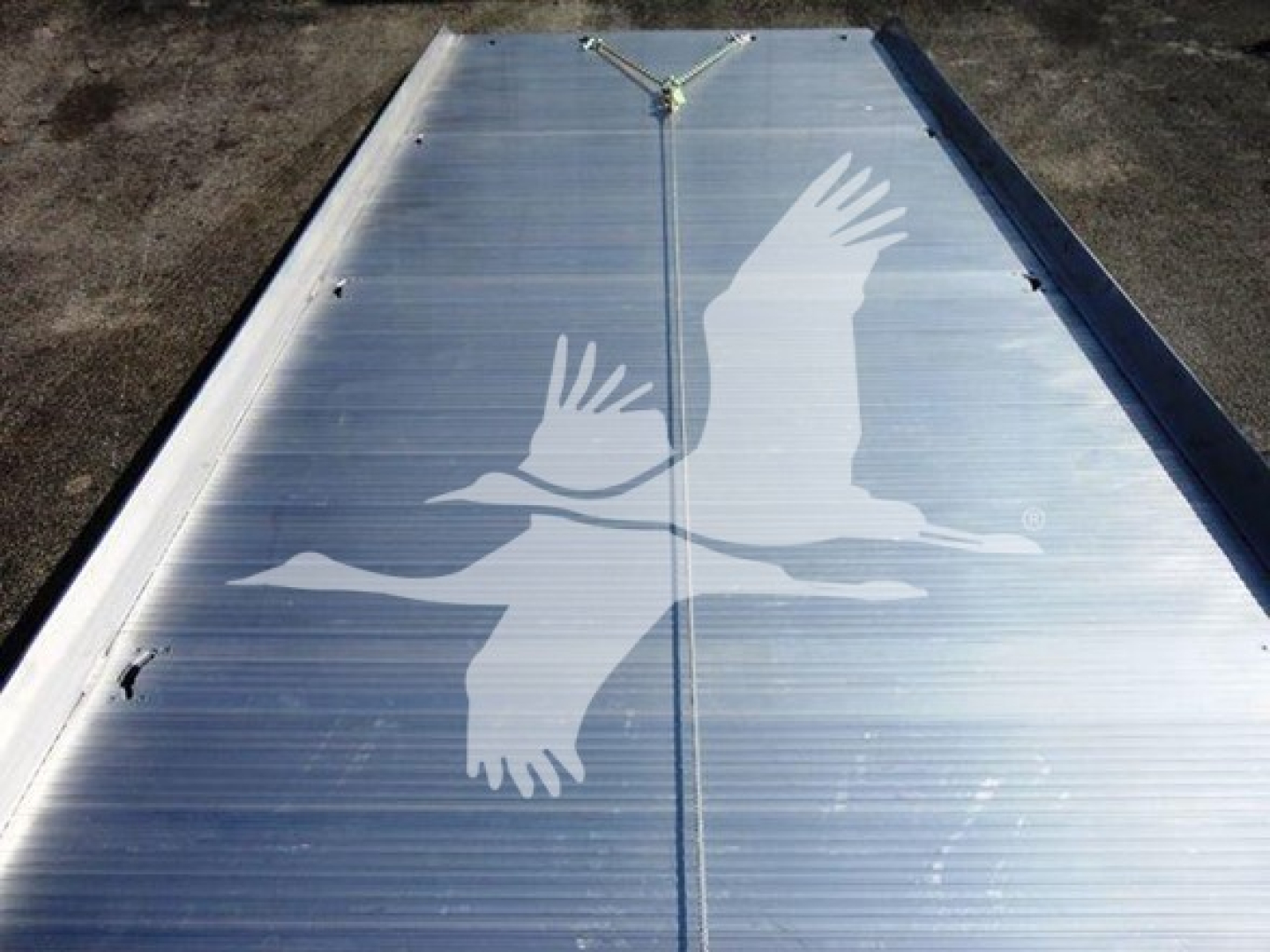Flatbed truck bed with silver aluminum surface and a large white bird decal in flight.