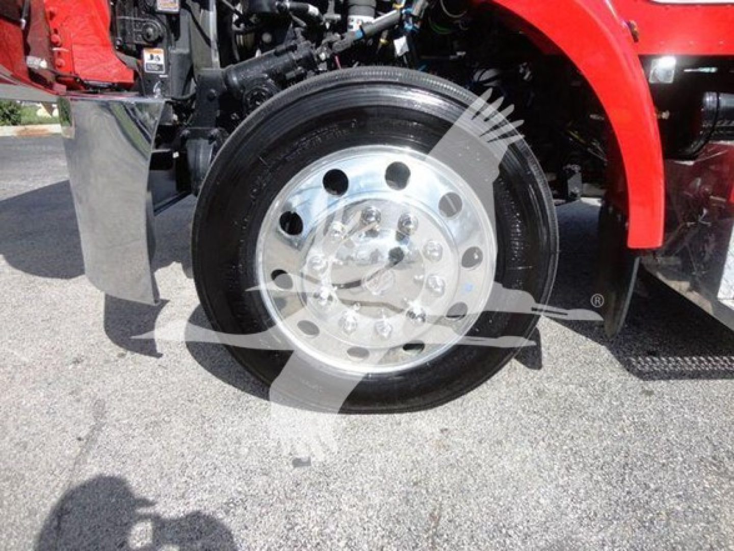 Peterbilt 337 rollback truck wheel assembly showing front wheel with polished aluminum rim and tire, red body panel nearby.