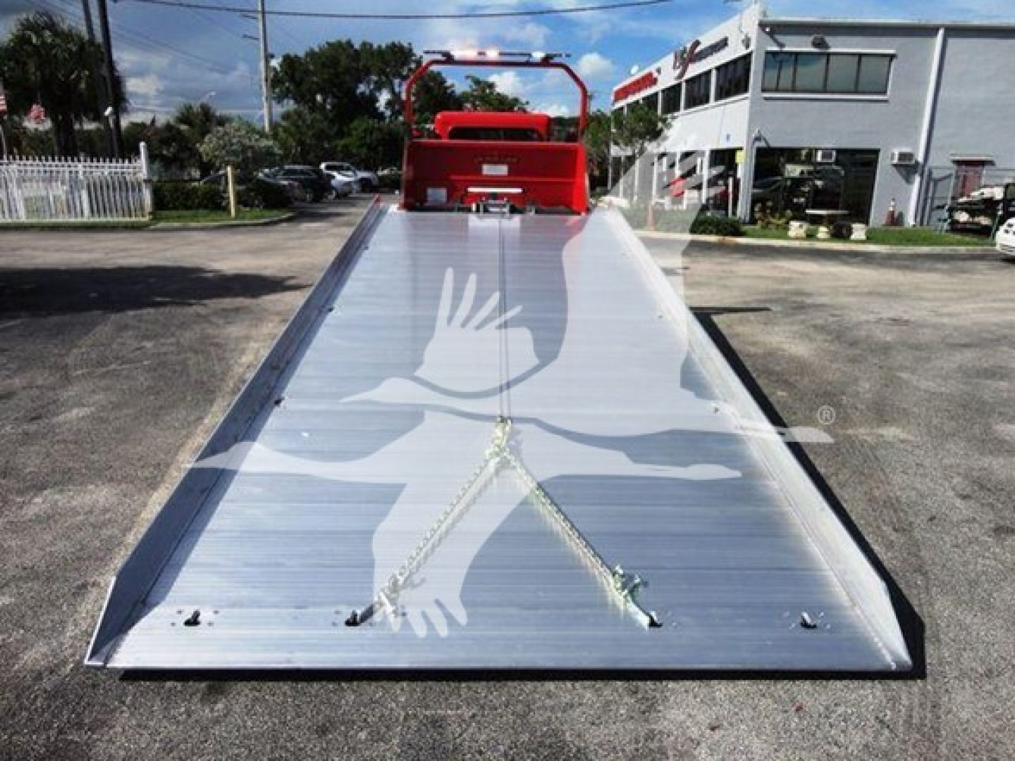 Peterbilt 337 rollback bed with aluminum ramp extension and safety chains, viewed from front end at a dealership lot.