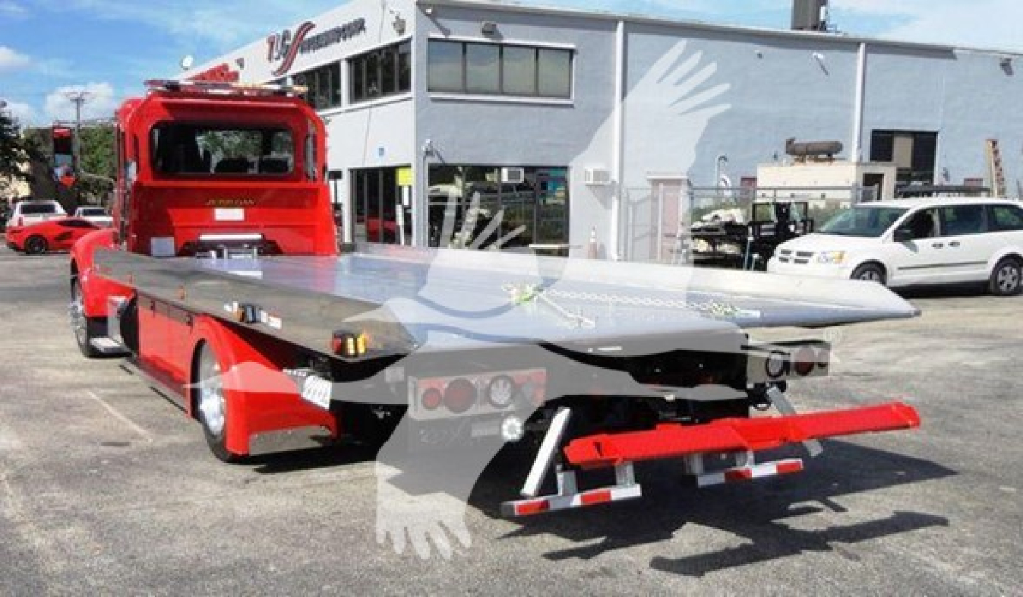 Peterbilt 337 rollback wrecker rear view showing flatbed tiltbed and red chassis.