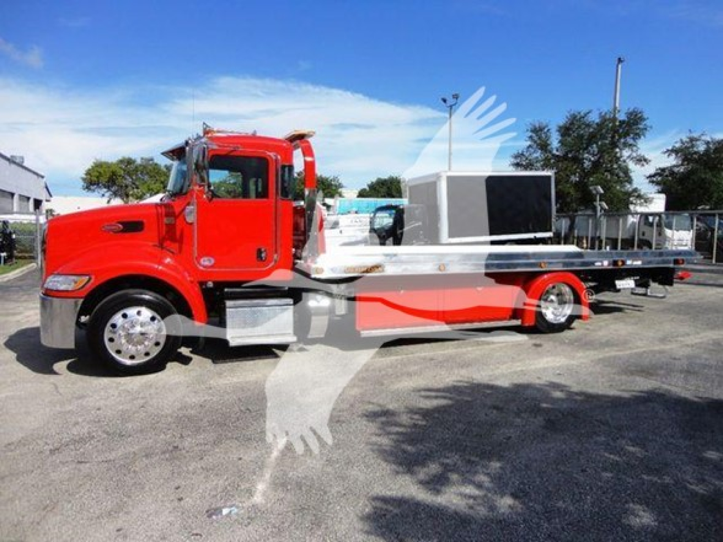 Peterbilt 337 rollback truck in red with flatbed and equipment trailer, side view.