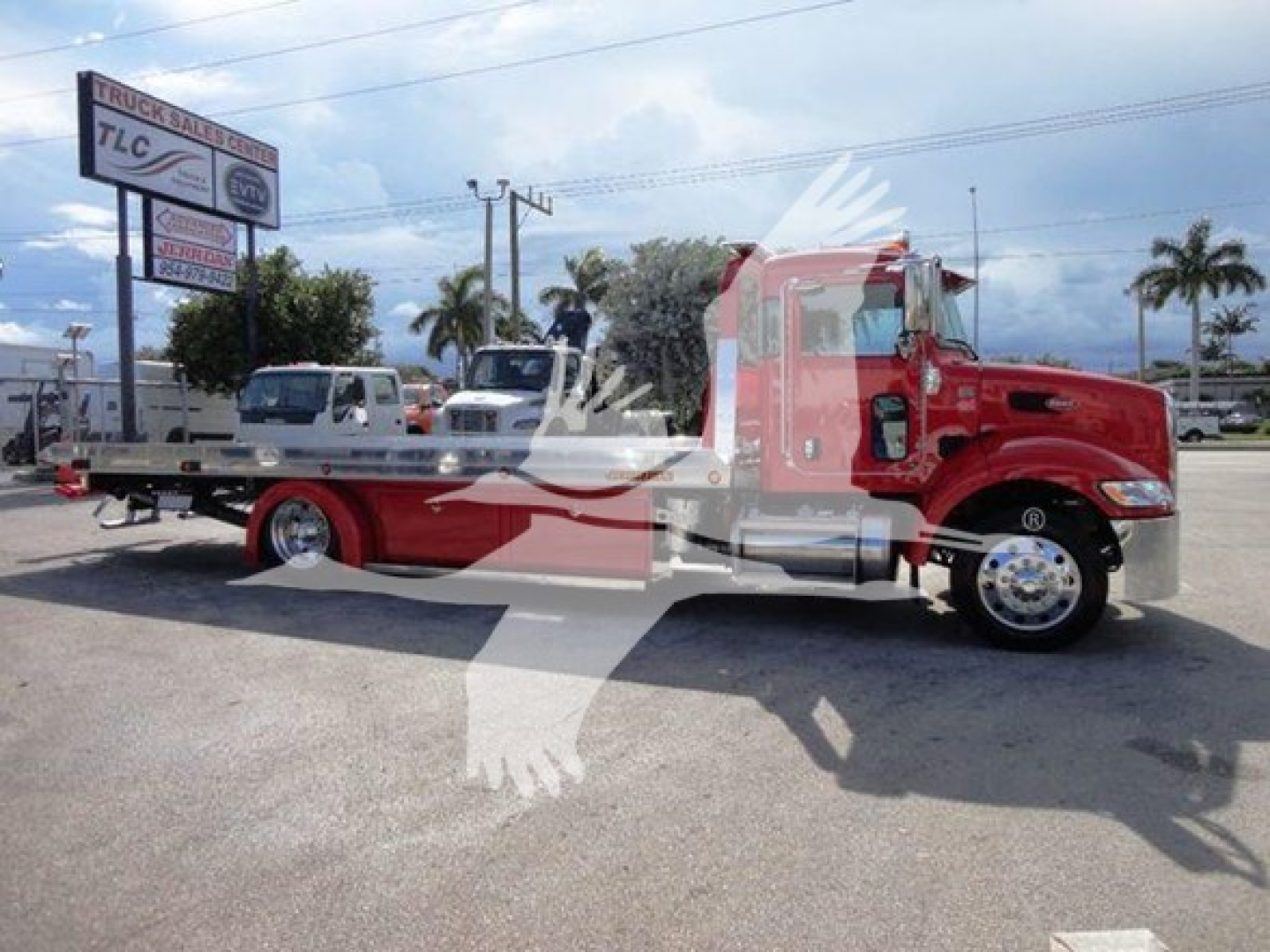 Peterbilt 337 rollback tow truck in red with flatbed, side view, dealership lot in background; watermark of white eagle across image.