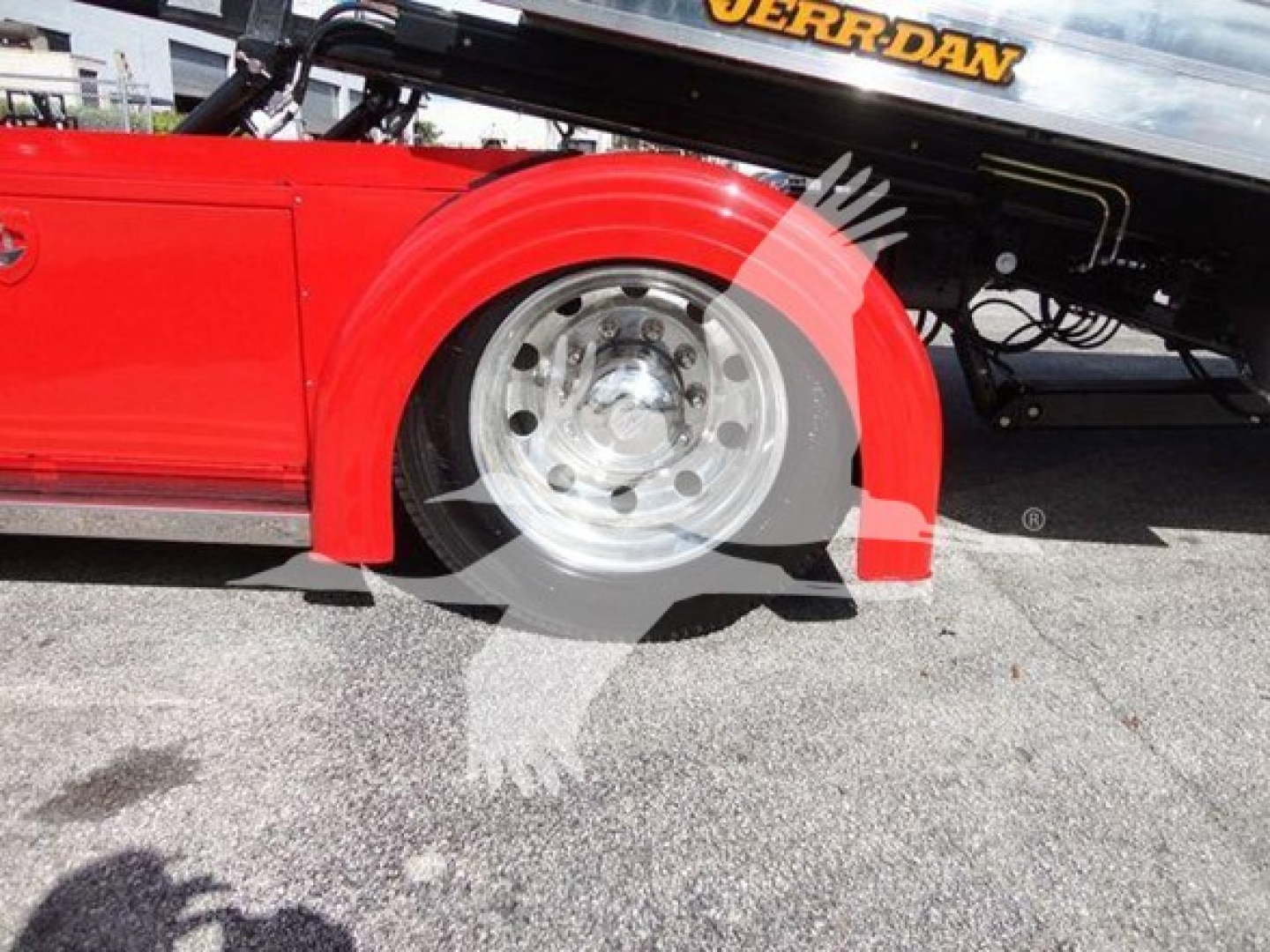 Peterbilt 337 rollback truck wheel area with red fender and chrome wheel, part of a rollback tow bed visible above.