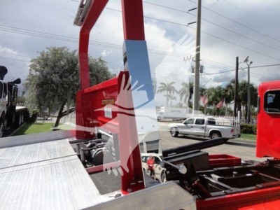 Vehicle equipment image showing a red rollback boom and platform on a Peterbilt 337 truck bed with metal decking and hydraulic components.