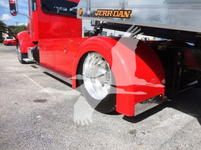 Tractor-back of a red 2022 Peterbilt 337 rollback truck showing rear fender and wheel with Jerr-Dan equipment on the bed.