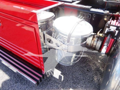 Truck engine bay detail showing aluminum round air filter housing and surrounding components in a red Peterbilt 337 rollback truck.