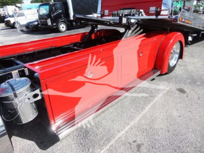 Peterbilt 337 rollback truck side showing bright red painted body and chrome wheel well, fuel tank, and frame components.
