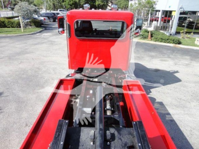 Peterbilt 337 rollback truck cab and chassis viewed from rear with red cab, extending frame rails, and hydraulics in center.