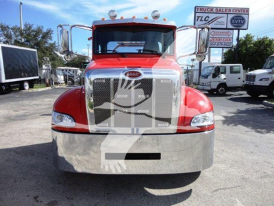 Peterbilt 337 rollback truck front view in red with chrome grille, bumper, and cab mirrors; appears in a dealership lot.