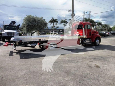 Peterbilt 337 rollback wrecker showing red cab and flatbed, side view with dual rear wheels and lettering on the cab