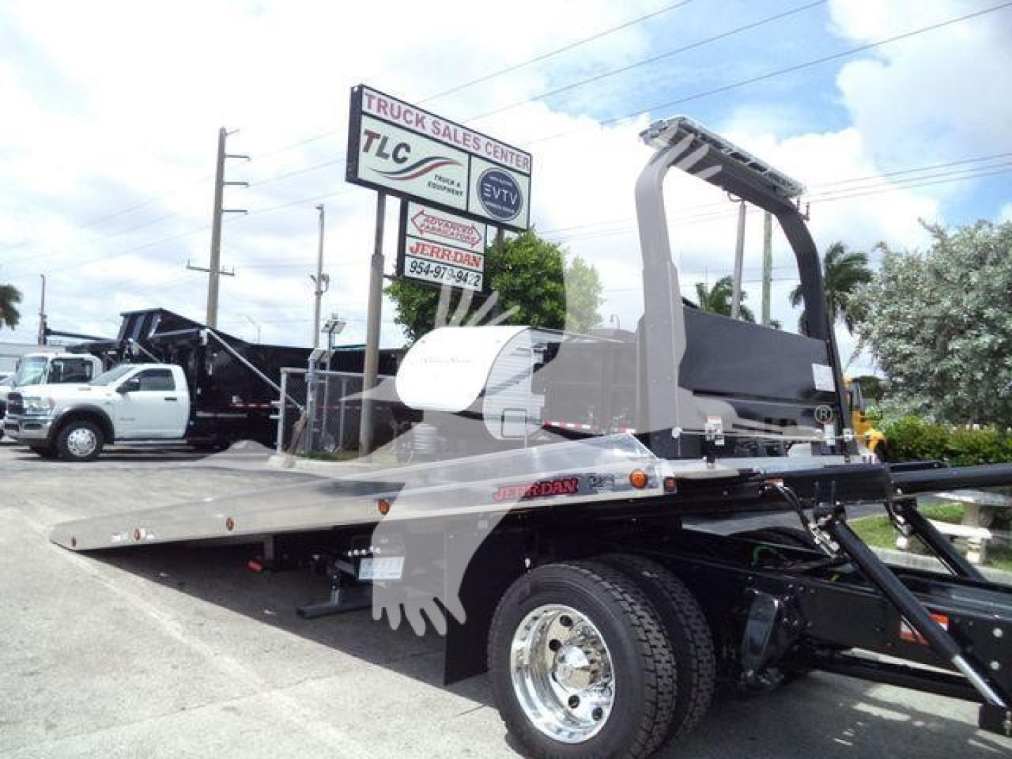 Flatbed rollback tow truck in a dealership lot, Freightliner M2 106 chassis with hydraulic wrecker mount and towing equipment visible.