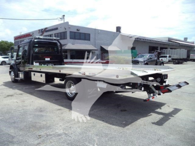 Truck bed rollback platform attached to a Freightliner M2 106 cab in a dealership lot showing tow truck flatbed and rear ramps.