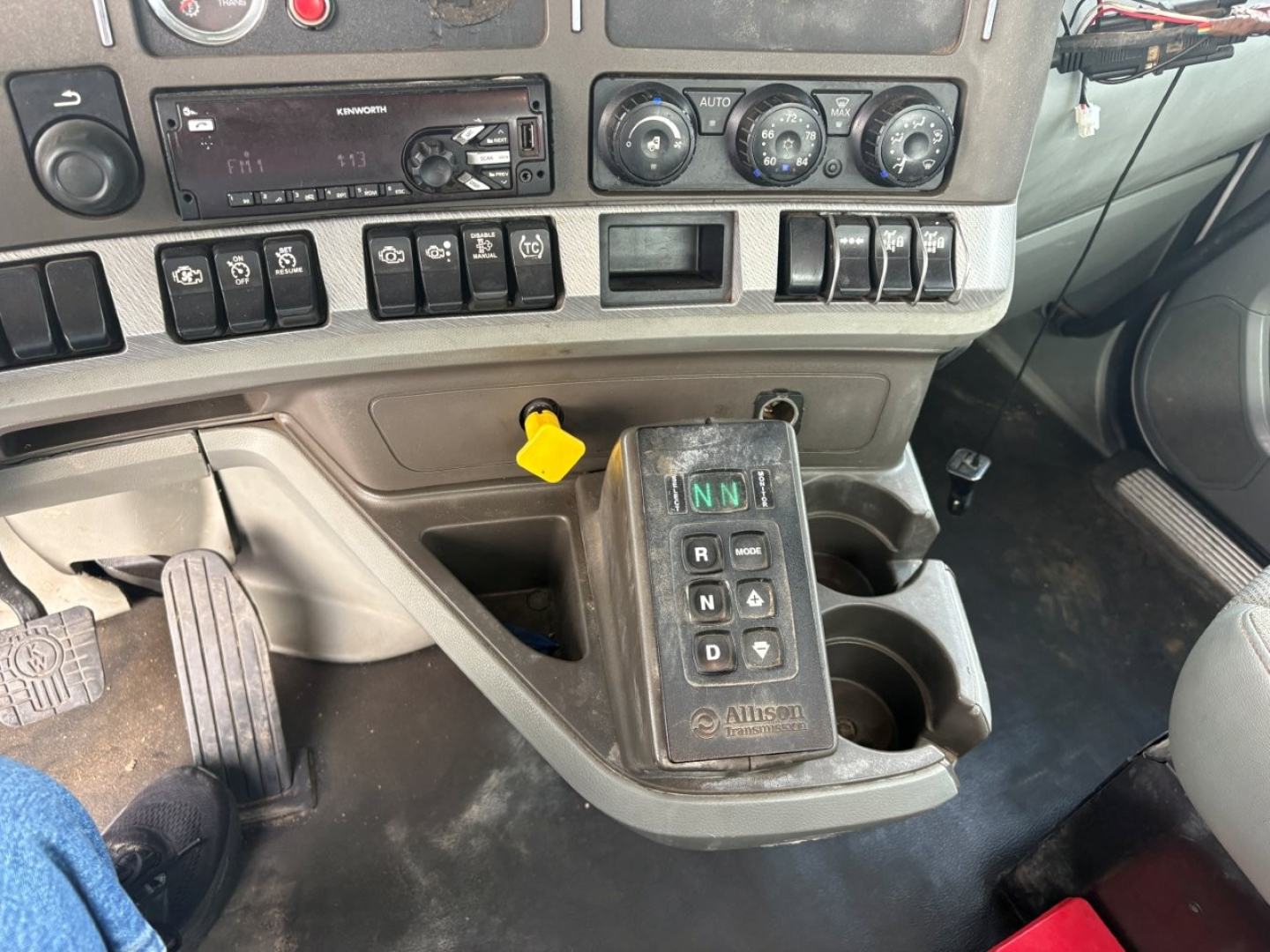 Kenworth T880 cab interior showing gear selector with push buttons, dashboard controls, and center console with yellow ignition/lock switch.