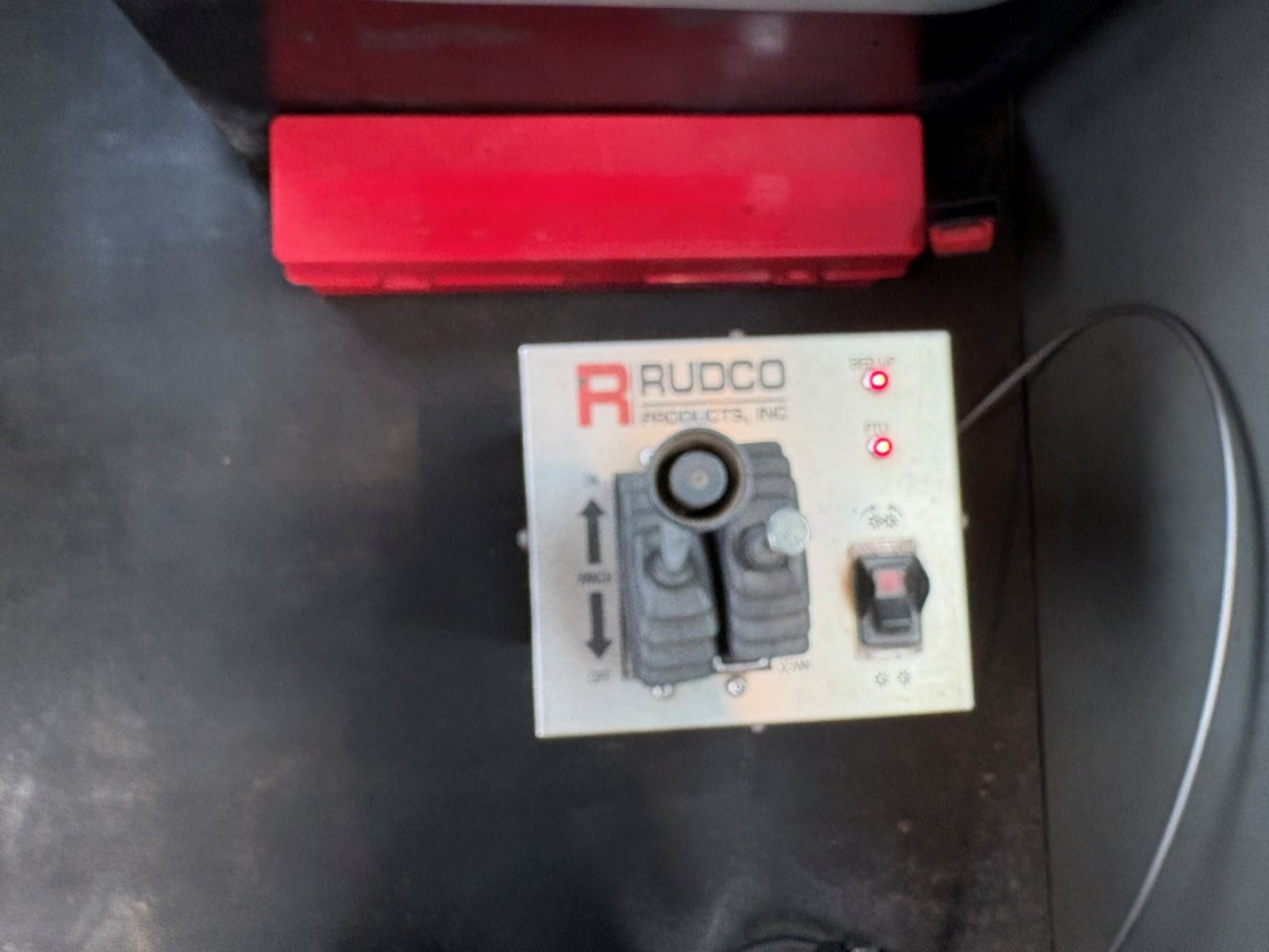 Kenworth T880 truck bed view showing RUDCO control panel with levers and buttons, part of roll-off system. Text 'RUDCO' and arrows on panel.