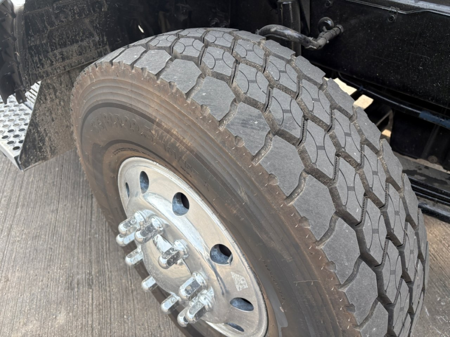 Kenworth T880 wheel and tire view in the front axle area showing tire treads and wheel hub. 
