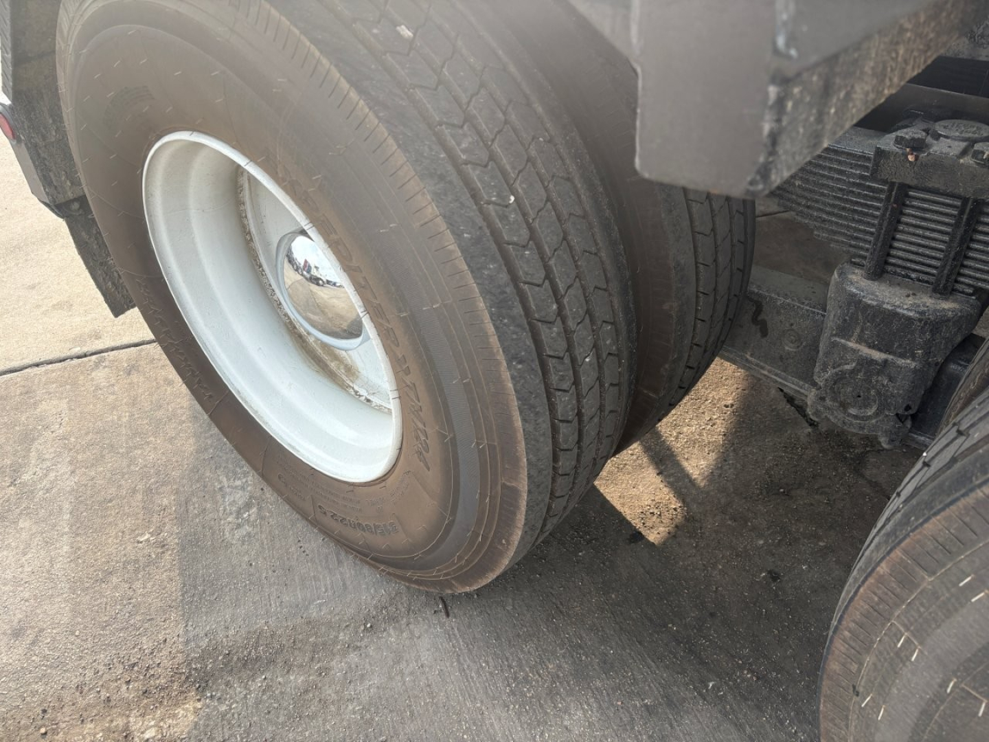 Kenworth T880 wheel and dual rear tire view showing front wheel and suspension components.