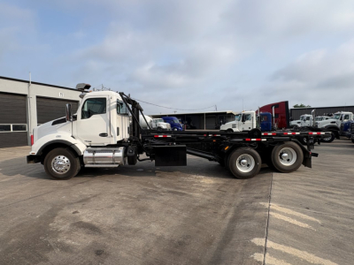Kenworth T880 roll-off truck side view showing chassis and cab with long flatbed and three-axle rear suspension.