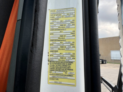 Vehicle VIN plate on Kenworth T880 showing GVWR and axle ratings, door jamb sticker with load specs and vehicle identifiers.