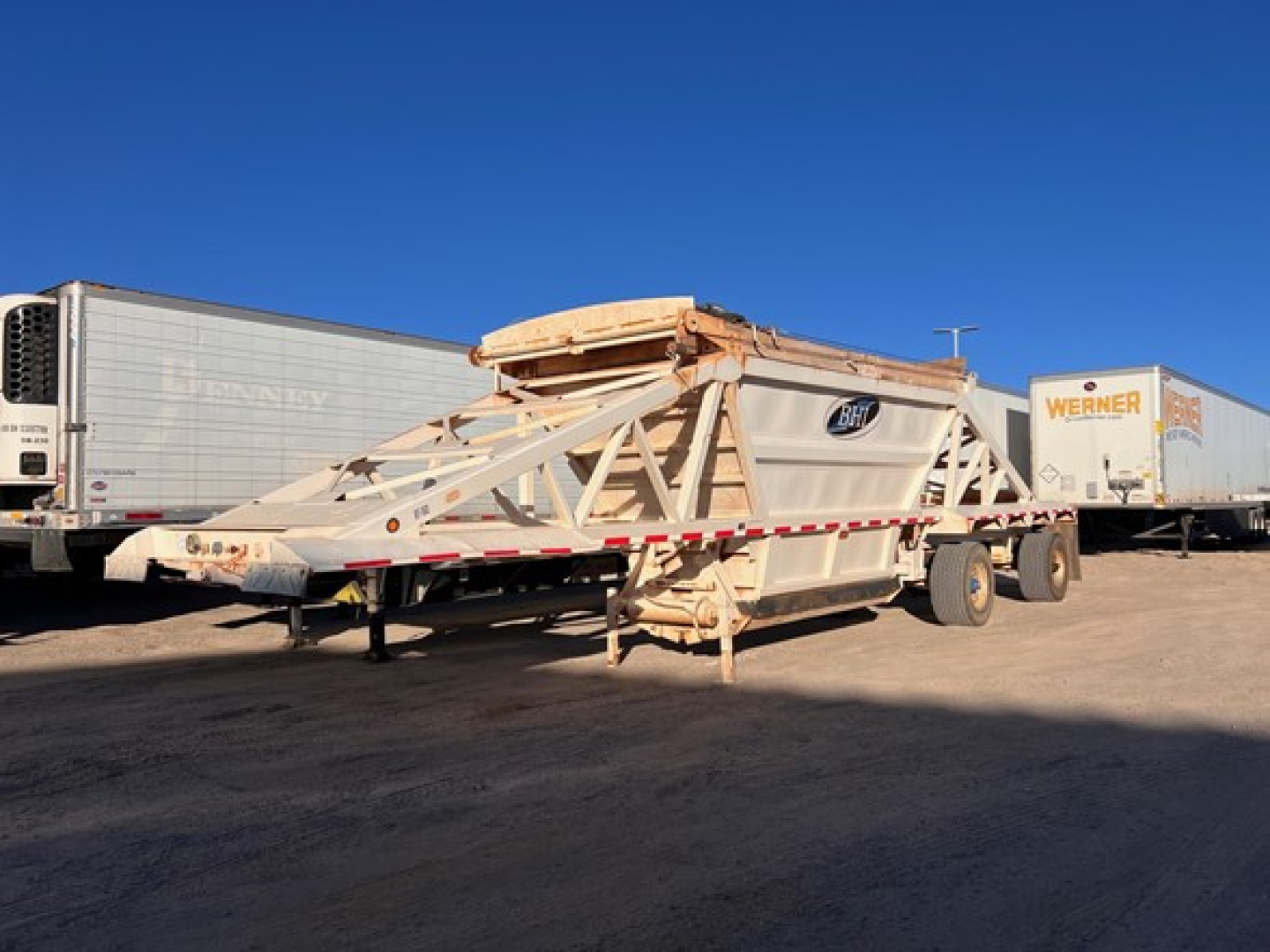 Manac light-weight bottom dump trailer in serviceable condition, long bottom body with truss framework and multiple support beams, attached to dual-axle tandem with hitch.