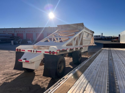 Manac light weight bottom dump trailer shown in an outdoor lot, white framework with tri-axle configuration and angled sides.