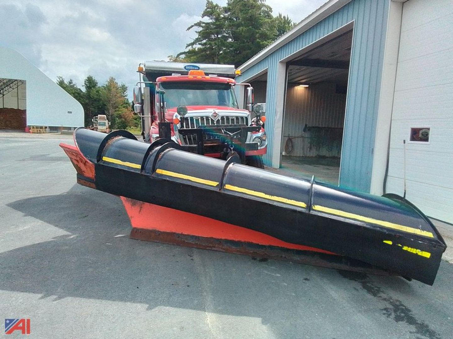 Truck-mounted snow plow attached to a 2014 International WorkStar 7600 dump truck in a yard, front view with plow blade and cab visible.