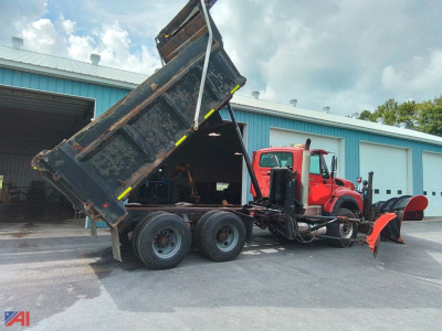 Dump truck with plow attached in-service International WorkStar 7600 dump truck with raised dumping bed and snow plow blade at front.