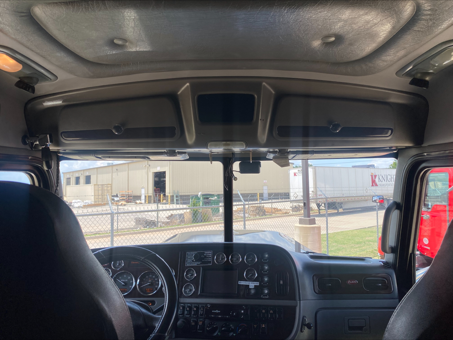 Peterbilt 389 cab interior front view showing dashboard, steering wheel, and overhead cab area.