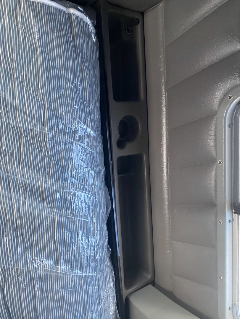 Peterbilt 389 truck interior side view showing seat with protective cover and doorway storage compartments.