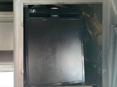 Truck cab interior showing an In-dash storage or cabinet with a small Dometic appliance or device in a recessed panel.