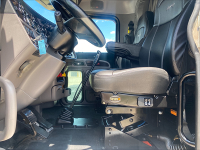 Peterbilt 389 truck interior cab showing driver seat and steering wheel with controls, gear selector, and dashboard; VIN/stock info not visible in image.